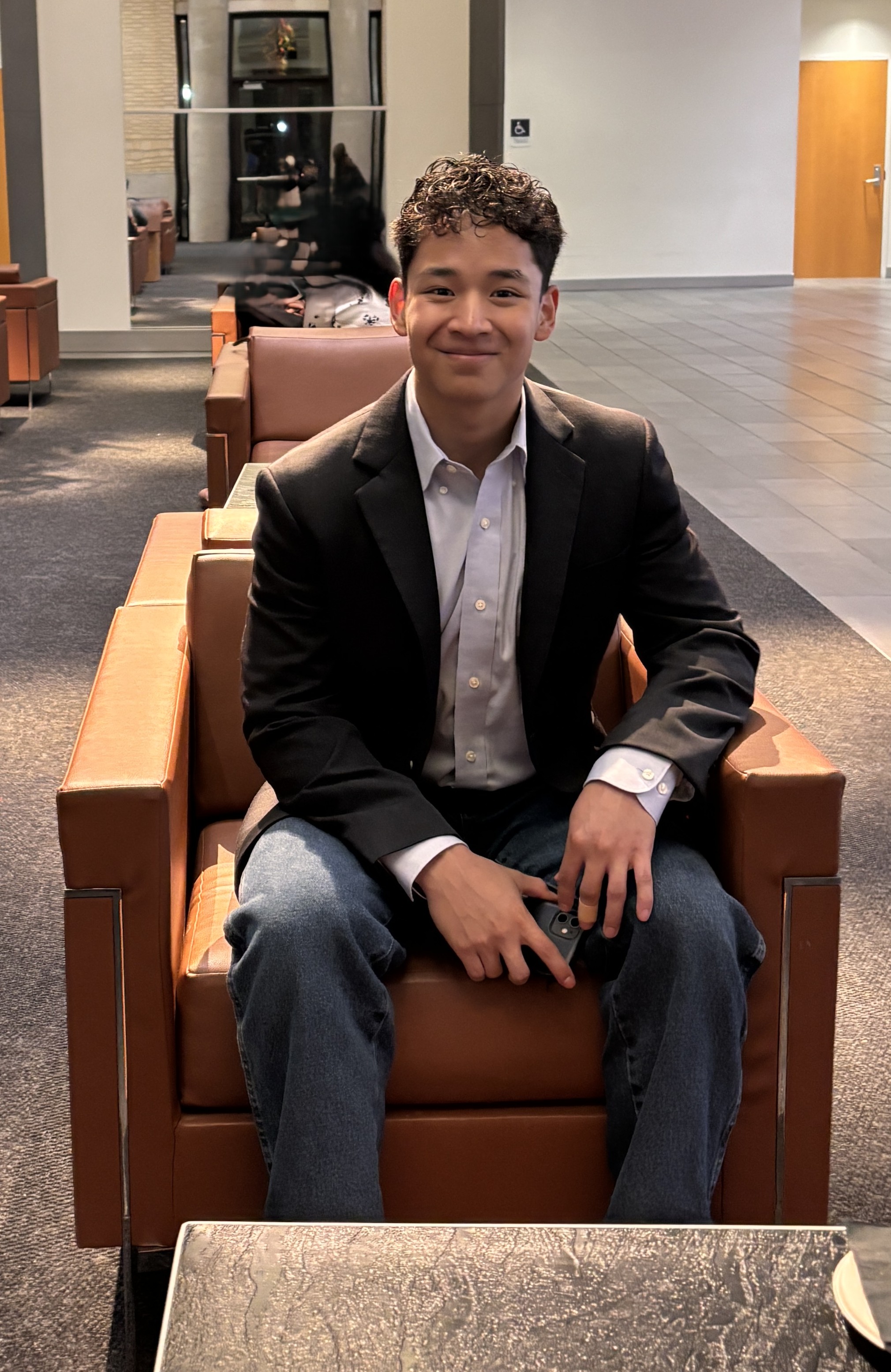 David Garudo seated in a lounge wearing a dark blazer and smiling at the camera.